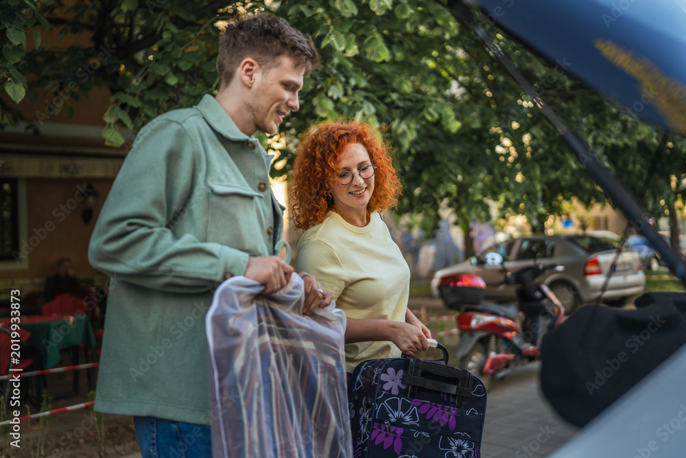 Naklejka premium Couple packing clothing and luggage into car trunk for travel