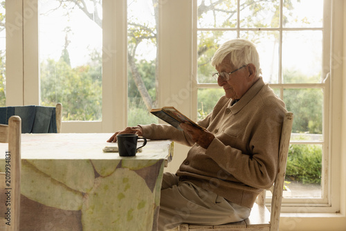 elderly man at table reading a book