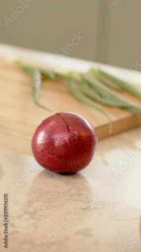 Vertical video: Pulling back camera showing red onion on counter, board, knife, green beans to cook