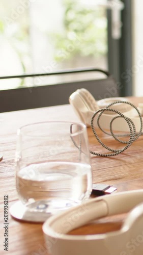Vertical video: Panning camera bringing clear glass toward center on table, showing headphones USB