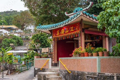 Lamma Island, Hong Kong, China: traditional Chinese village temple surrounded by tropical vegetation and rural houses near Ko Long Village on the island of Lamma. 
