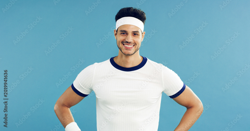 Fototapeta premium Portrait, smile and tennis with man on studio space for health, retro sports or wellness. Confidence, fitness and proud with happy person on blue background for competition, game or hobby as player