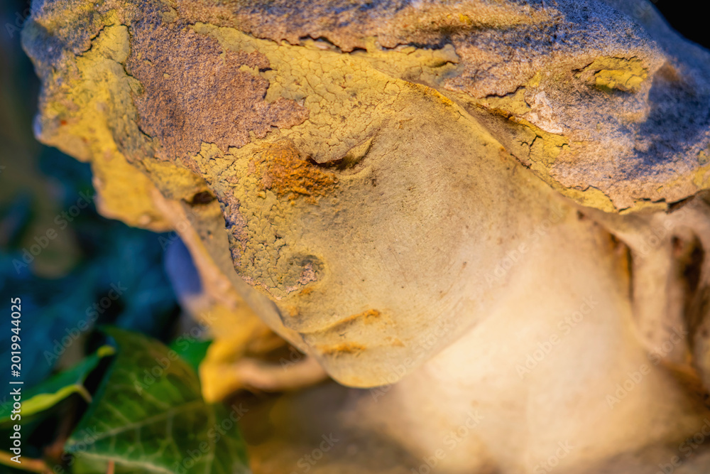 Obraz premium Weathered angel statue closeup with peeling stone texture and ivy