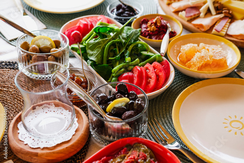 turkish breakfast served outdoors on sunny day, food variety, olives, jam, vegetables