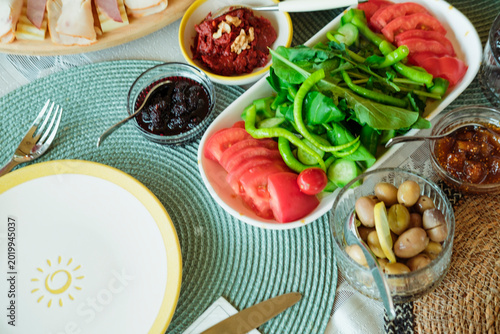 turkish breakfast served outdoors on sunny day, food variety, olives, jam, vegetables