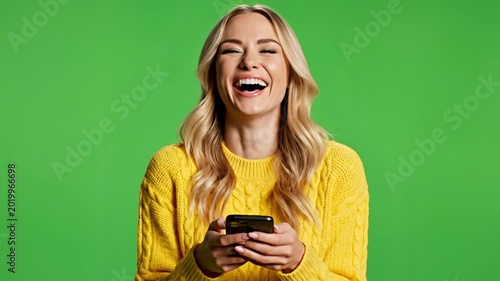 Young Woman Laughing While Using Her Smartphone on a Green Screen Background.