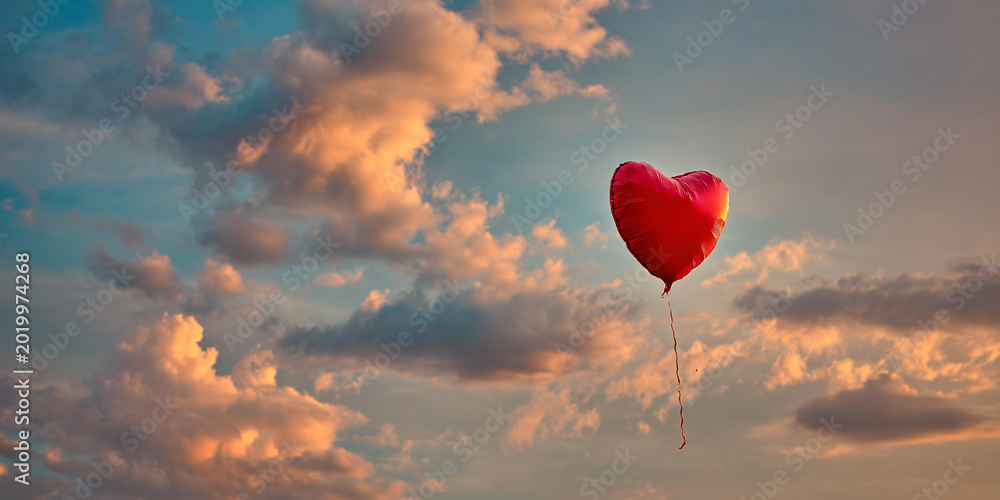 Fototapeta premium Red Heart Shaped Balloon Floating in Cloudy Sunset Sky