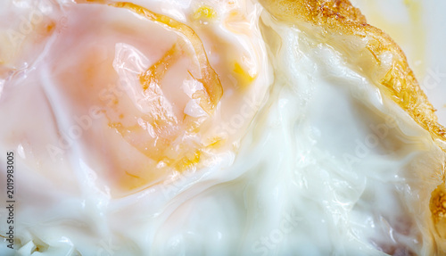 Photos Close-up macro shot of  fried egg with a rich golden-orange runny yolk partially