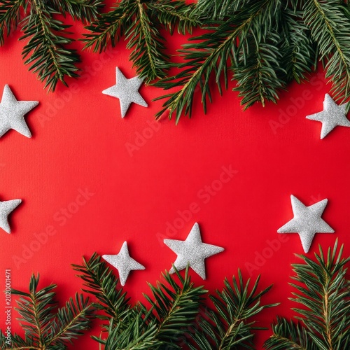 Decorative Silver Stars and Greenery Arranged on Red Background for Holiday S...