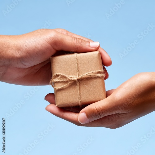 Hands Holding a Wrapped Gift Box on a Blue Background in a Simple Setting