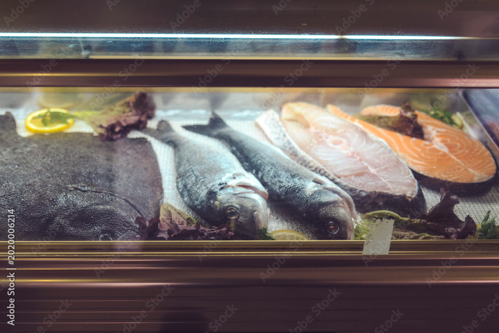 Φωτογραφία Fresh Raw Fish and Salmon Steaks in a Refrigerated Restaurant Display Case
