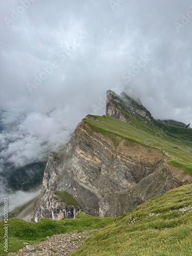 Seceda mountain ridge after rain with dramatic clouds over the Odle Group and green alpine meadow, Dolomites, Italy