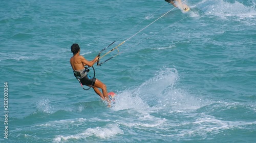 Man enjoy kitesurfing, jumping over the ocean waves during a sunny summer day in vietnam