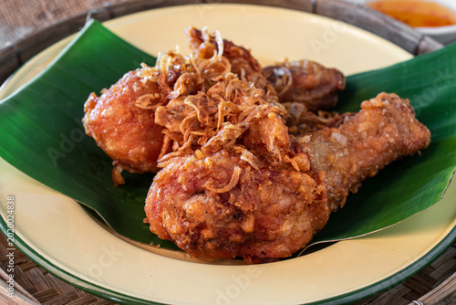 Canvastavla Authentic Hat Yai fried chicken drumsticks topped with crispy fried shallots served on a green banana leaf in a wooden tray