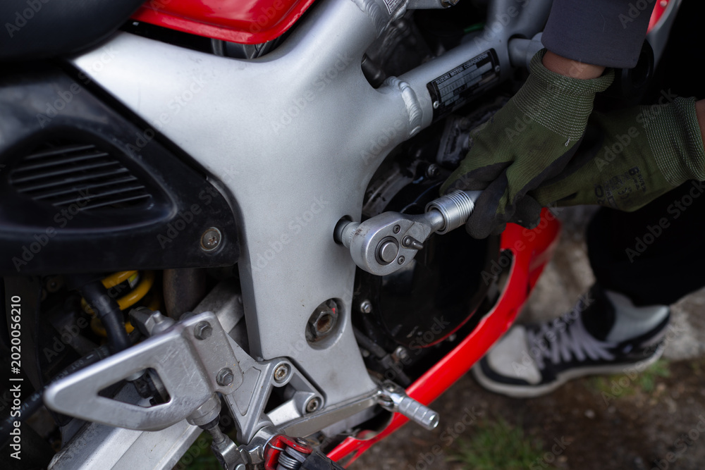 Fototapeta premium Mechanic servicing a motorcycle engine and footpeg area