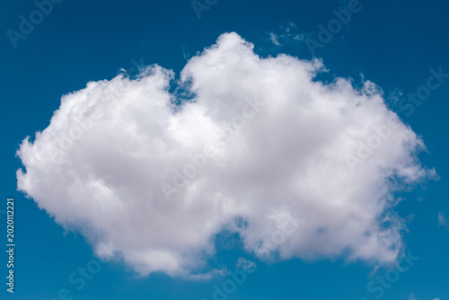 Fotografía A single, fluffy white cumulus cloud floating isolated against a brilliant and clear deep blue sky background on a sunny day, showcasing beautiful natural textures and light