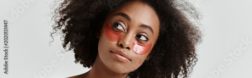 Young woman with curly hair embracing beauty rituals in a serene studio setting