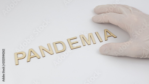 Pandemia scritta su legno. Una mano con un guanto di lattice tiene la scritta