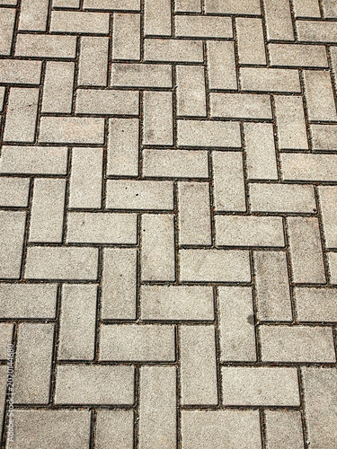 Herringbone Pavement - light gray herringbone pattern consisting of rectangular stone pavers on a pedestrian walkway. The image captures the rhythmic, geometric masonry