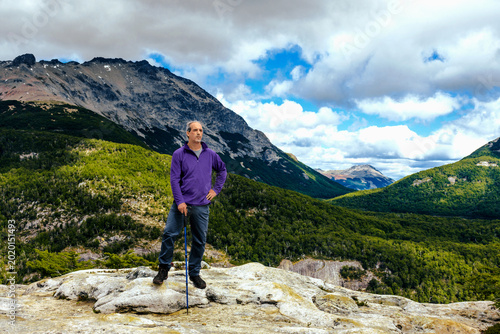 Hiker in a purple jacket standing on a rocky mountain ridge overlooking the valley at Mirada del Doctor lookout, Argentina.
