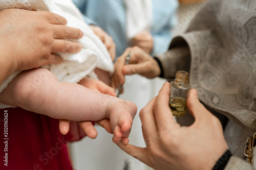Tableau sur toile Priest anointing newborn baby foot with holy oil during Orthodox baptism ceremon