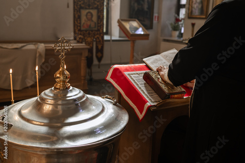 Canvastavla Priest reading holy bible near baptismal font during Orthodox church ceremony cl