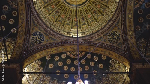 Slow motion 4K footage of a magnificent mosque interior in Cairo, Egypt. The video showcases a grand chandelier, ornate Islamic dome decorations, and rich architectural details.