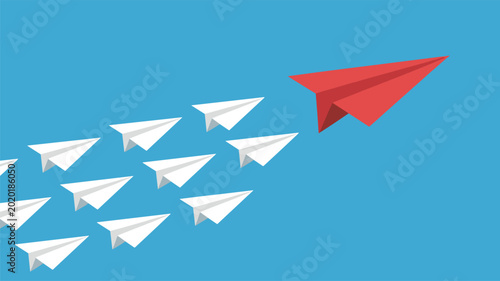 A single red paper airplane leads a formation of white paper airplanes across a clear blue sky.
