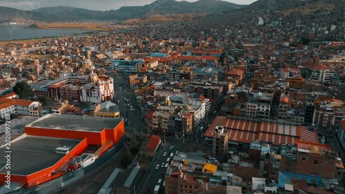Drone aerial view of Puno, a historic city located on the shores of Lake Titicaca in southern Peru. Urban neighborhoods, Andean hills, and the vast waters of the world’s highest navigable lake create 