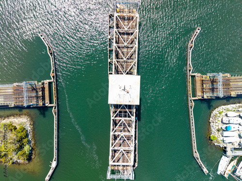 Photos Mystic River Railroad Bridge overhead view, a high-angle aerial drone shot capturing the historic swing truss railway bridge rotating open above water and coastal boat marinas in Mystic, Connecticut