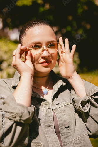 Fotografie Portrait of beautiful young woman in stylish rimless glasses and denim jacket ad