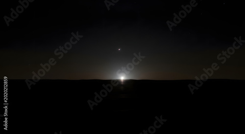 A bright light on the horizon at night with stars in the dark sky