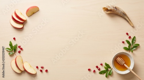Rosh Hashanah greeting card background with copy space, flat lay top view of jewish holiday symbols on a smooth wooden table