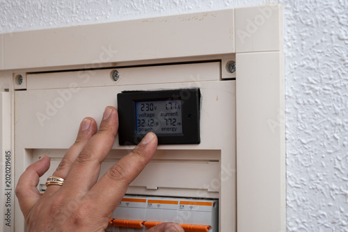 фотографія Hand monitoring electrical energy usage on smart meter display