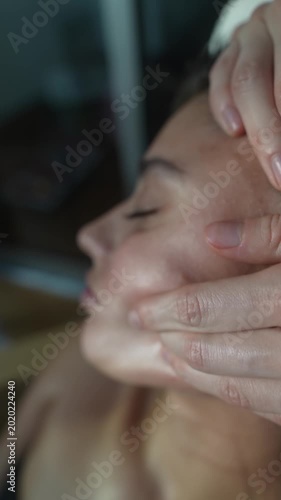 Calm woman receives expert facial massage under gentle ambient lighting