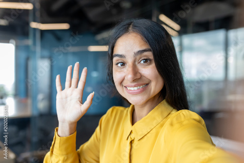 Canvas Print Close-up photo of a young Indian woman in an office, greeting and talking to the