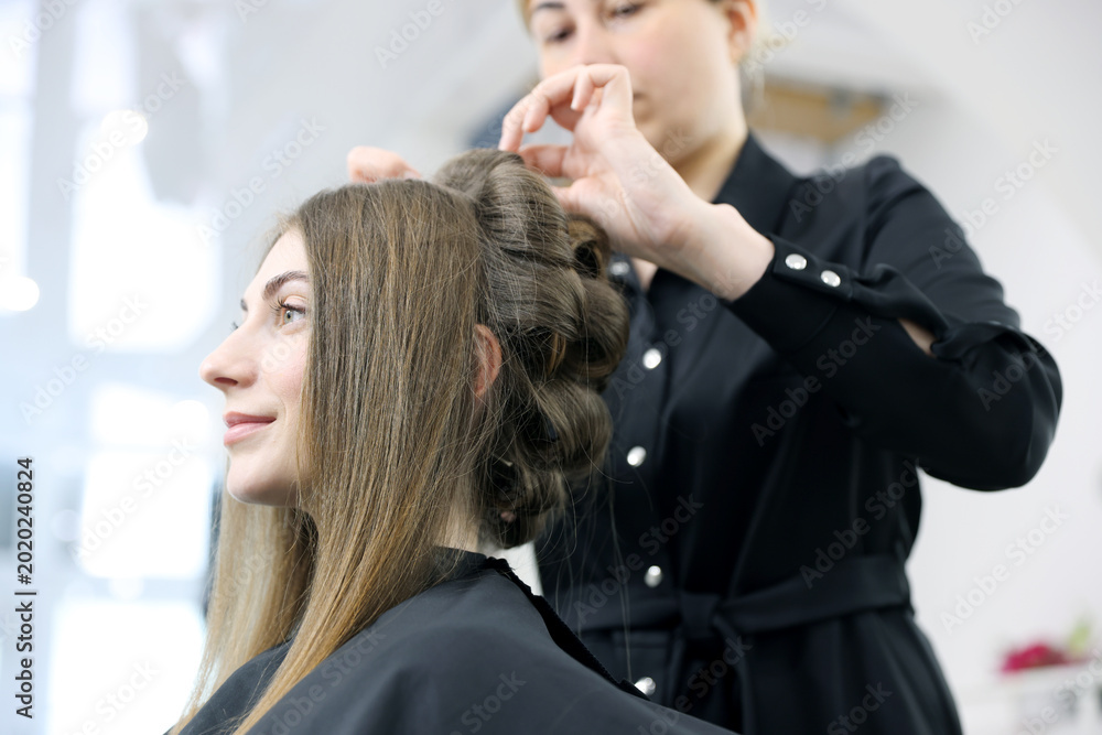 Fototapeta premium Stylist styling woman's hair in beauty salon, selective focus