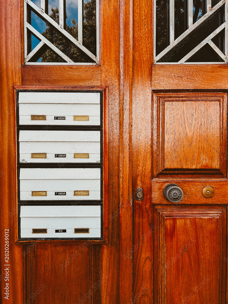 Φωτογραφία Wooden entrance door with mailboxes and glass panels, vintage urban facade detai