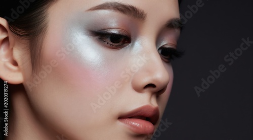 Young asian woman with sparkling eye makeup and glossy lips. Face beauty portrait with highlighted skin  soft blush and defined brows. Fashion style  perfect skin.