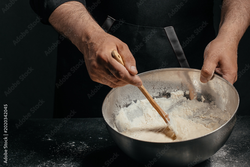 Ταπετσαρία Professional baker mixing sourdough dough in metal bowl in dark kitchen for arti