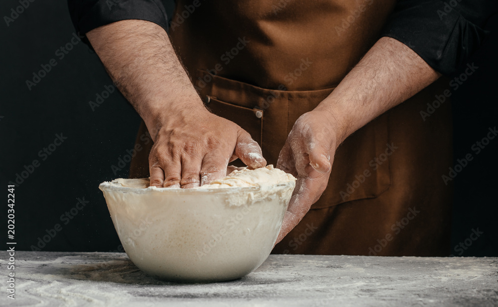 Fototapeta premium Professional baker kneading sourdough dough in glass bowl for artisan bakery advertising