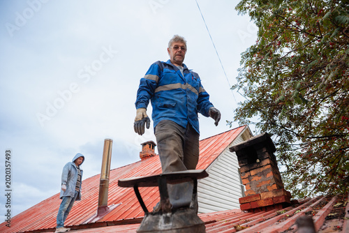 Obraz na plátne Chimney sweep working on house roof