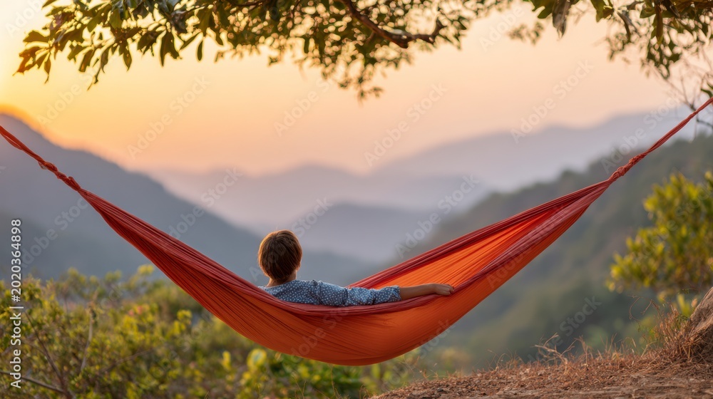 Fototapeta premium A serene sunset view of a young person relaxing in a hammock amidst the tranquil mountains, surrounded by nature and vibrant hues of orange and pink.