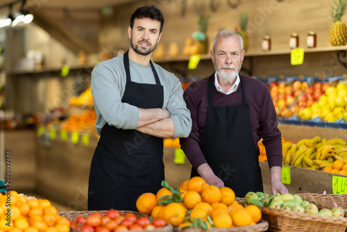 Portrait of two male salesperson wearing an apron in the vegetable department of a supermarket