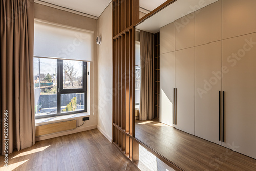 Фотография Modern bedroom interior with wooden slat partition and built-in wardrobe