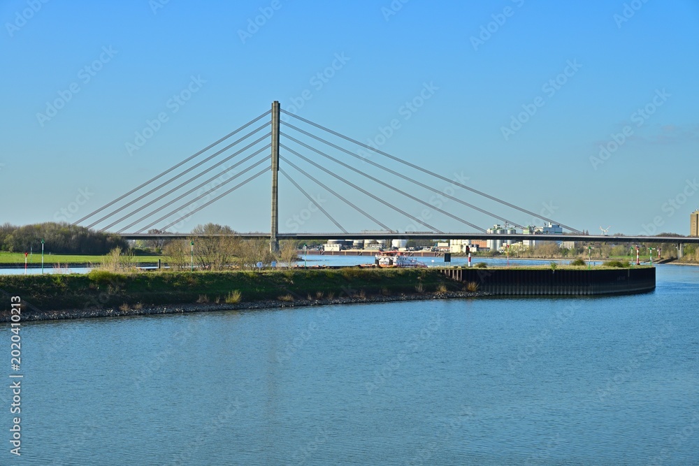 Fototapeta premium Modern cable stayed bridge over wide river in industrial landscape