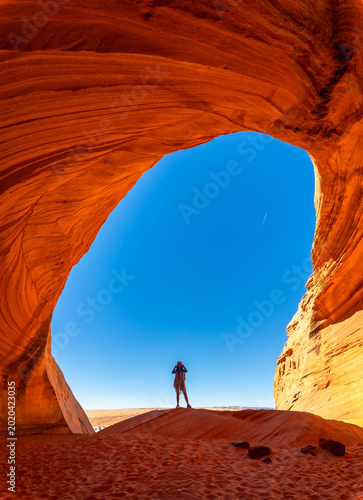 Person standing beneath biidi the arch cave in page