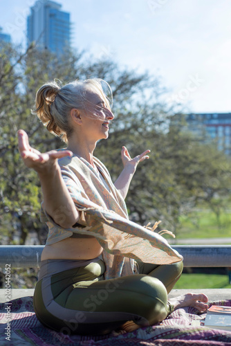 Smiling mature woman practicing yoga with open arms outdoors