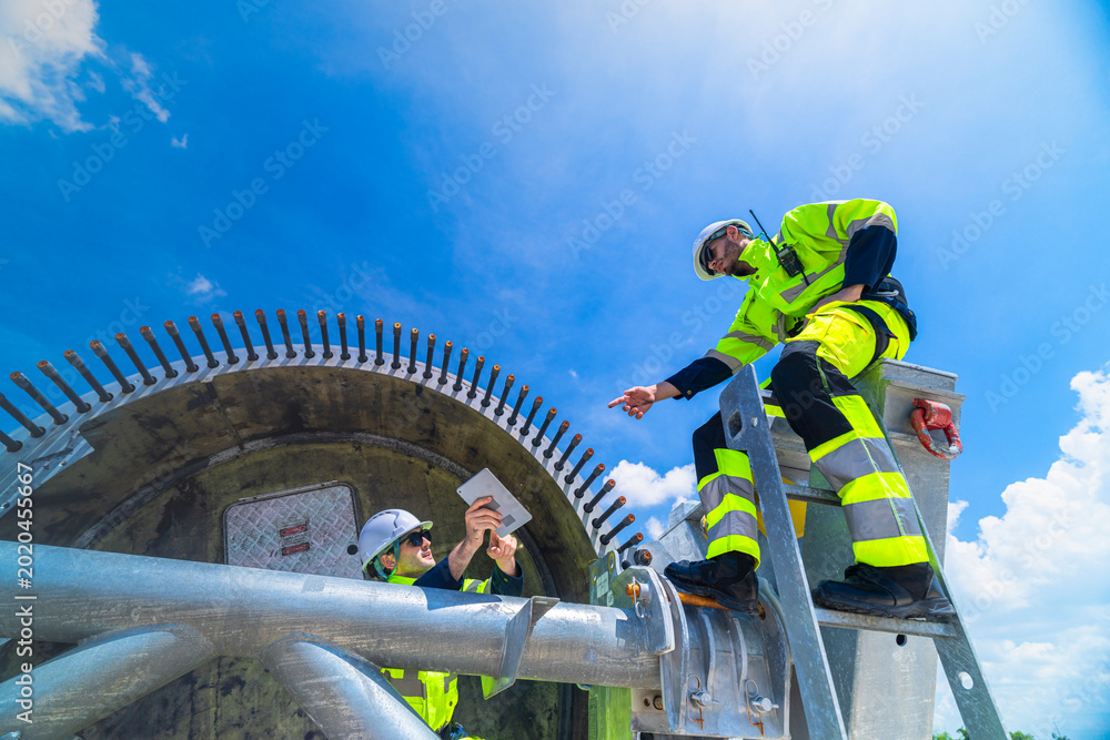 Ταπετσαρία Technical wind farm staff discussing installation plans and pointing towards turbine structures at a large-scale renewable power generation site