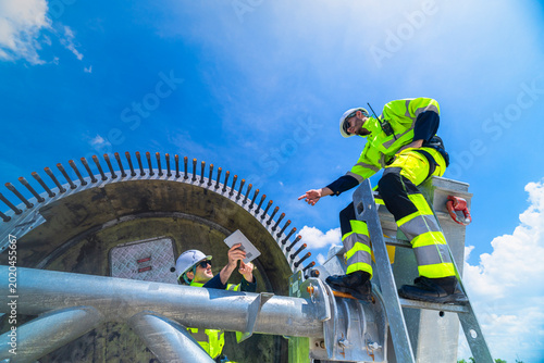 Foto Technical wind farm staff discussing installation plans and pointing towards turbine structures at a large-scale renewable power generation site